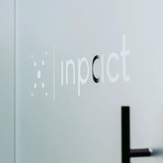 Het Inpact-logo op de glaswand van het kantoor